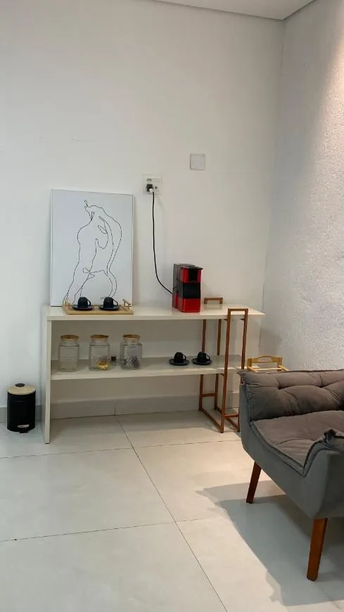 Cantinho do café com máquina, xícaras e poltrona
